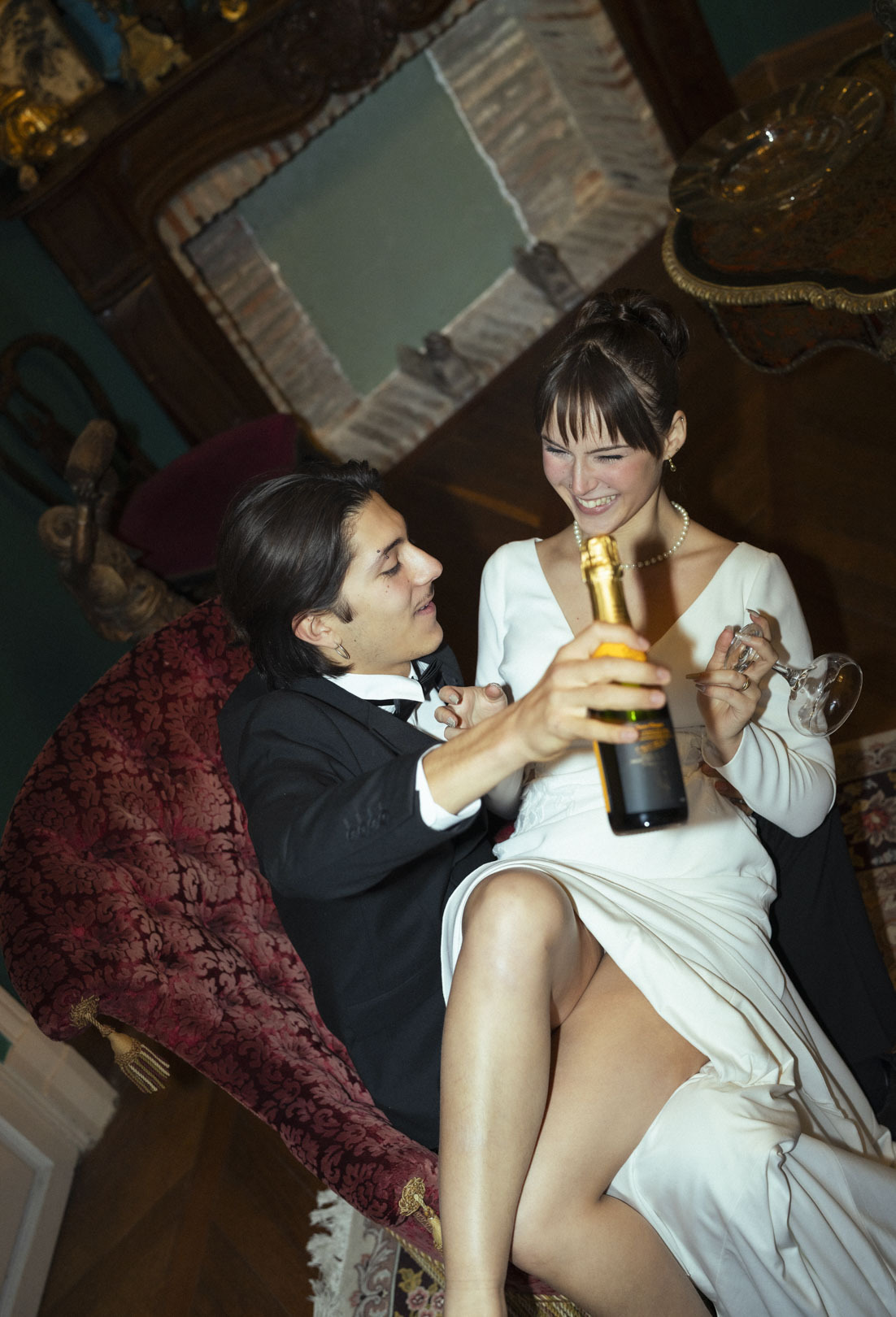 Couple de mariés qui s'amusent dans un moment d'intimité complice avec une coupe de champagne